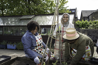 Three women smiling as they tend to plants in a wildlife garden