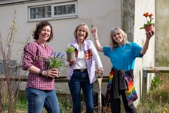 Three people holding plants