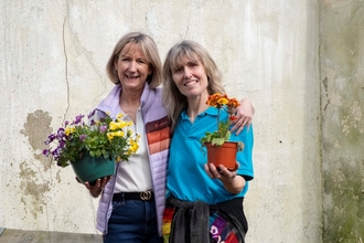Two women holding flowers and smiling