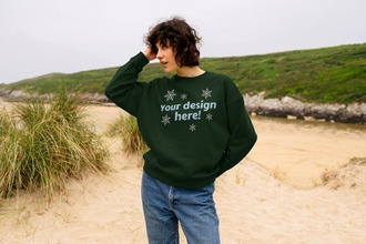 woman stood on a beach wearing a green jumper that reads "your design here"