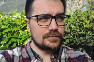 Rob Gordon stood outside in a garden, with a hedge visible behind him