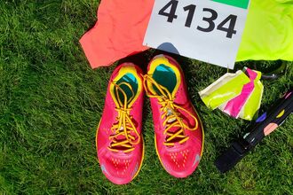 Running shoes, marathon race bib (number), runners gear on a grassy lawn