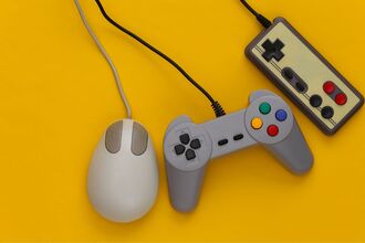 A mouse and two gaming controllers on a yellow background