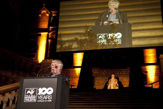 Bill Oddie stood at a podium giving a speech in an auditorium at The Wildlife Trusts' centenary event