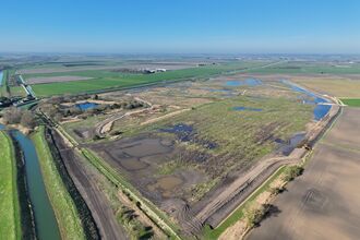 Aerial view of river restoration works featuring new wetland habitats, meandering channels and reconnected floodplain within farmland.