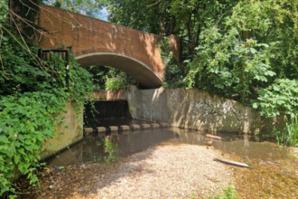 A bridge and artificial concrete channel through which the River Rib runs