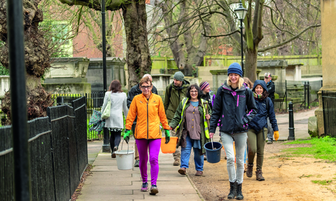Group of people walking in London with gardening equipment in late winter