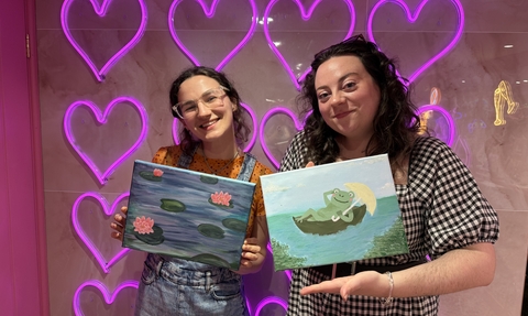 Two women holding paintings