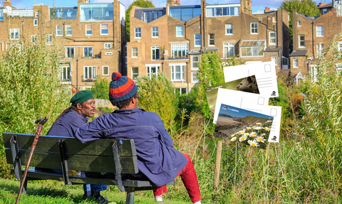 Two men talking on a bench overlooking terraced housing, and superimposed postcard images