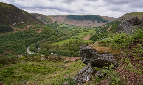 A view of a mountain from a mountaintop with a stream running through the centre