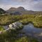 Suilven mountain in Scotland in the background. In the foreground is boggy land, with grassy mounts and pools of water