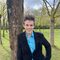 Matt Browne is stood in a park in front of a tree. He is smiling broadly and leaning against the tree trunk