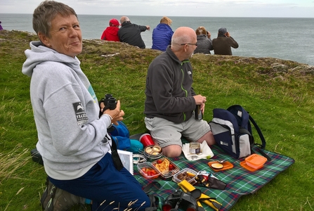 Sue sits on the cliffs with her binoculars