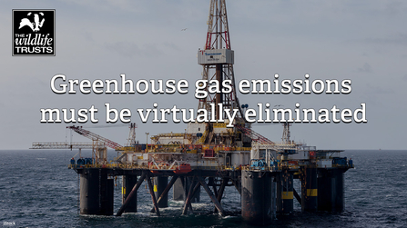 Oil platform in the sea with the text: "Greenhouse gas emissions must be virtually eliminated"