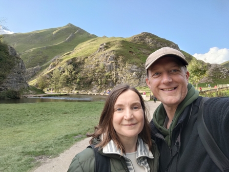 A man and a woman taking a selfie with a set of hills in the background
