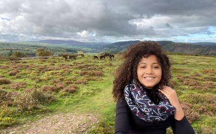 Jamey, standing on a hill in exmoor, with exmoor ponies in the background