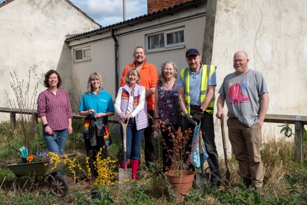 A group of people with gardening tools in front of a white building