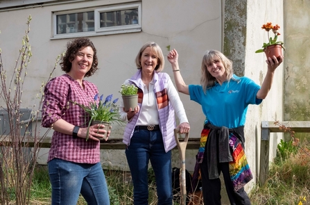 Three people holding plants