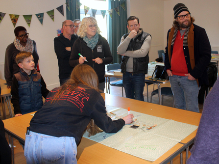 People discuss ideas stood around a table.