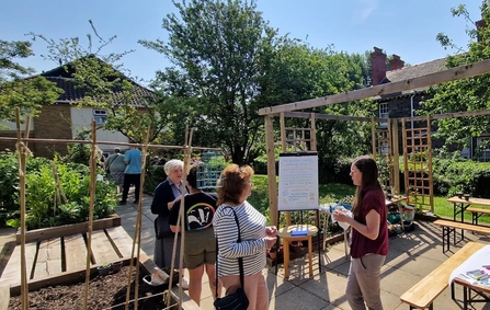 Several people gather together in a community garden.