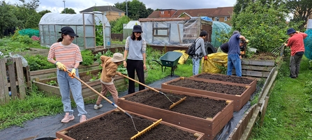 Adults and children build raised beds in a community garden.
