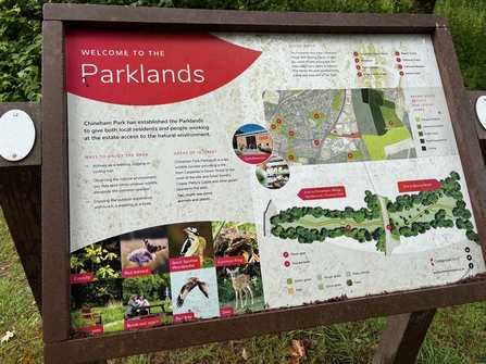 An interpretation board showing a site map of Parklands and information about some of the wildlife seen there, including woodpecker and deer