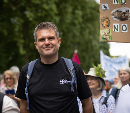 The Wildlife Trusts Chief Executive Craig Bennett walking with a group of people at a large march for nature. He is smiling straight at the camera
