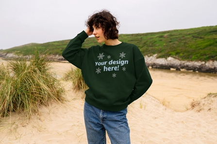 woman stood on a beach wearing a green jumper that reads "your design here"