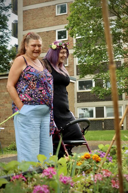 Two people looking at colourful plants. One person uses a walking aid.
