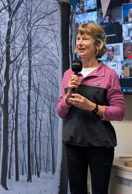 Anna Williams stood in front of a screen, smiling and speaking into a microphone