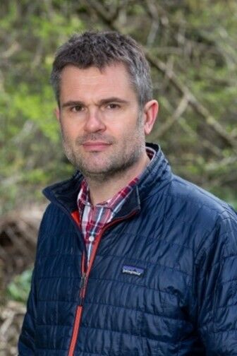 Craig Bennett smiling outside in forest