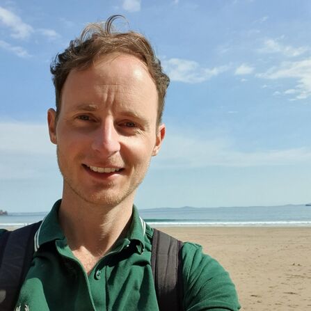 Alec Taylor smiling standing on the beach 