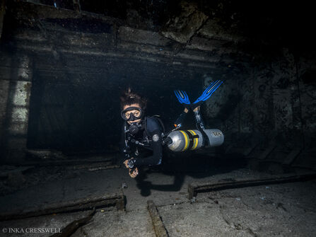 Inka Cresswell in scuba gear swimming through a shipwreck