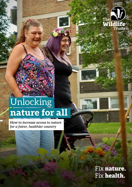 The front cover of a report called Unlocking nature for all: How to increase access to nature for a fairer, healthier country. Two women are stood side by side smiling at a large flower bed outside a block of flats