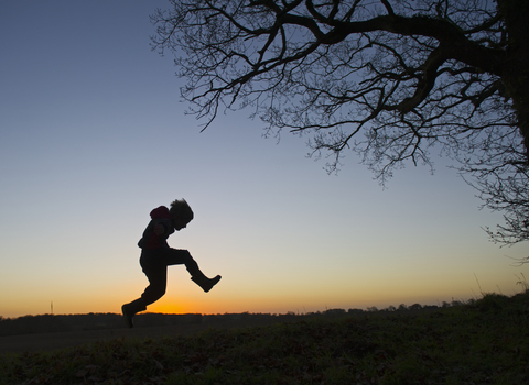 A silhouette of a child playing outdoors at sunset, The Wildlife Trusts