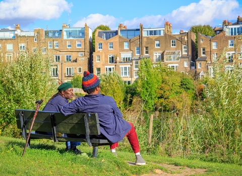 Two people sat on a bench in an urban park, talking