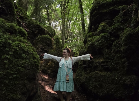 Jem stands between two mossy banks, her arms outstretched