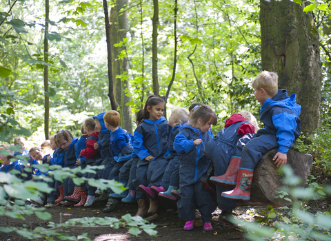 Small children in a wood wearing blue overalls