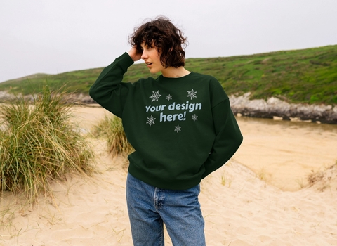 woman stood on a beach wearing a green jumper that reads "your design here"