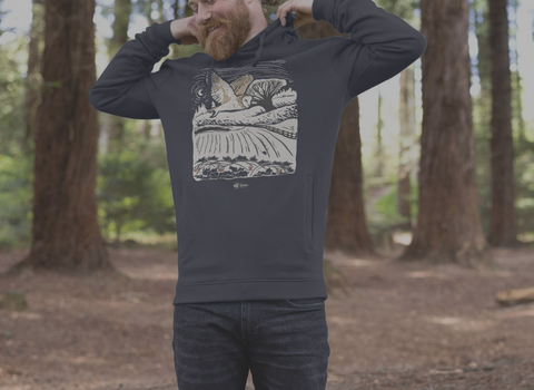 A man in a woodland wearing a hoodie with a graphic print of a barn owl