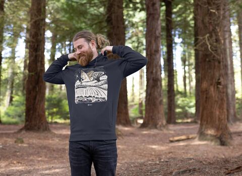 A man in a woodland wearing a hoodie with a graphic print of a barn owl