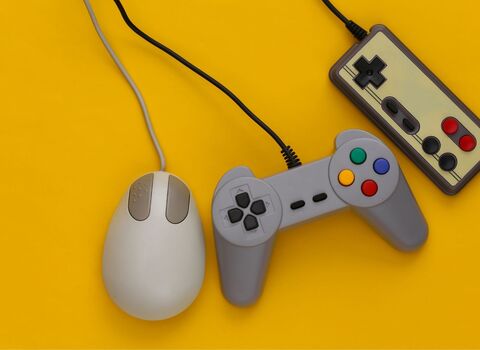 A mouse and two gaming controllers on a yellow background