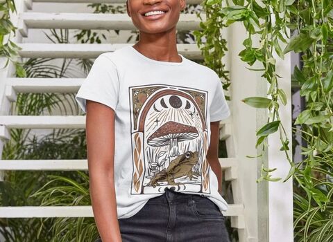 A woman wearing a t-shirt with an illustrated frog sat under a mushroom